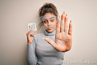 Young african american girl holding reminder paper with no word negative message with open hand doing stop sign with serious and Stock Photo