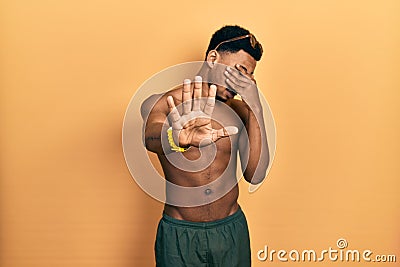 Young african american man wearing swimwear and swimmer glasses covering eyes with hands and doing stop gesture with sad and fear Stock Photo