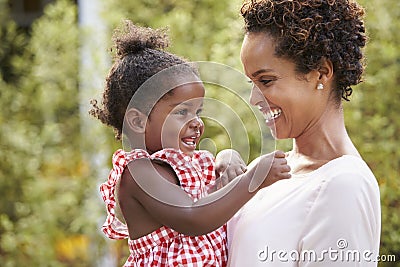 Young African American mother holds baby daughter in garden Stock Photo