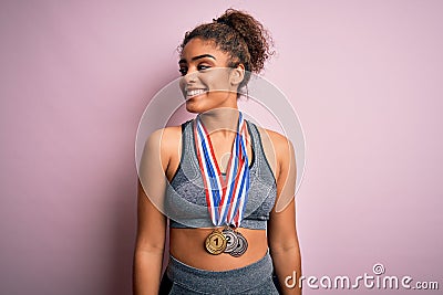 Young african american sporty girl doing sport winning medals over isolated pink background looking away to side with smile on Stock Photo