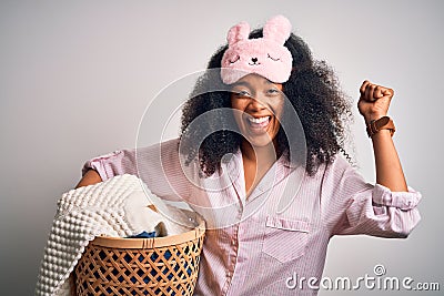 Young african american woman with afro hair wearing pajama doing laundry domestic chores screaming proud and celebrating victory Stock Photo