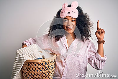 Young african american woman with afro hair wearing pajama doing laundry domestic chores surprised with an idea or question Stock Photo