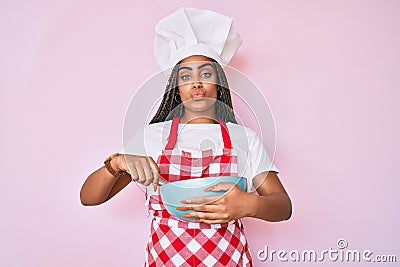 Young african american woman with braids cooking using baker whisk looking at the camera blowing a kiss being lovely and sexy Stock Photo