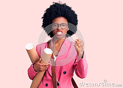 Young african american woman holding architect blueprints annoyed and frustrated shouting with anger, yelling crazy with anger and Stock Photo