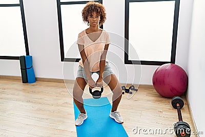 Young african american woman training using ketlebell at sport center Stock Photo