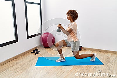 Young african american woman training using ketlebell at sport center Stock Photo