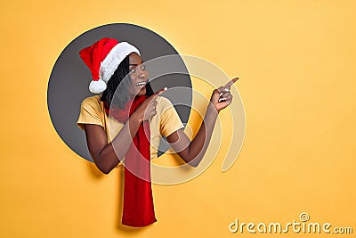 Young african american woman wearing christmas hat and scarf pointing to side. Christmas sale concept. Copy space Stock Photo