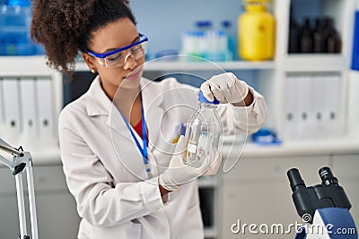 Young african american woman wearing scientist uniform closing bottle at laboratory Stock Photo