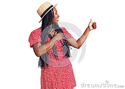 Young african american woman wearing summer hat looking proud, smiling doing thumbs up gesture to the side Stock Photo