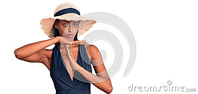 Young african american woman wearing swimsuit and summer hat doing time out gesture with hands, frustrated and serious face Stock Photo