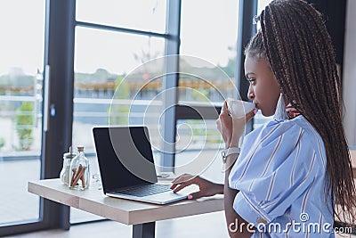 Young african american woman working with laptop and drinking coffee Stock Photo