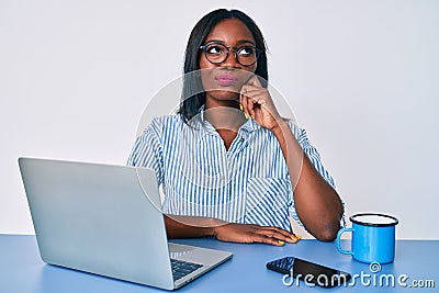 Young african american woman working at the office with laptop thinking concentrated about doubt with finger on chin and looking Stock Photo