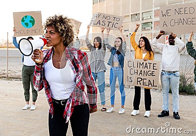 African American woman shouting through megaphone leading demonstration protesting against climate change. Stock Photo