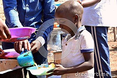 A young African boy being served food at a school feeding programme Editorial Stock Photo