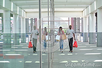 Young african couple drinking refreshing drinks and going shopping, walking outside the mall Stock Photo