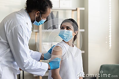 Young african doctor gluing patch on hand of indian woman. Stock Photo