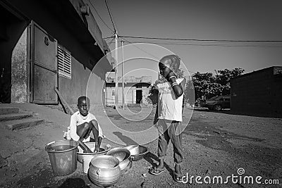 Young African girls washing the dishes in the street of Bamako i Editorial Stock Photo