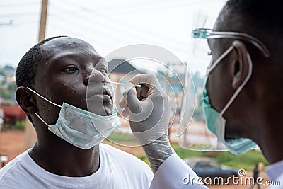 African lab scientist taking nasal sample from a man Stock Photo