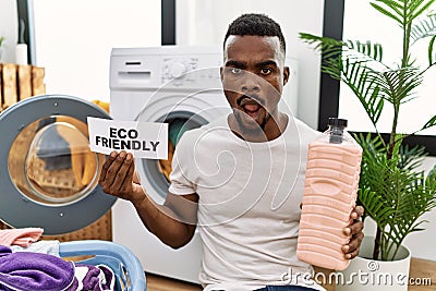 Young african man doing laundry holding eco friendly paper afraid and shocked with surprise and amazed expression, fear and Stock Photo