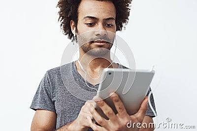 Young african man in headphones looking at tablet over white background. Stock Photo