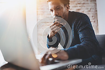 Young African man using laptop while sitting at his modern coworking place.Concept of business people full concentration Stock Photo