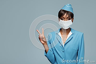 Young african stewardess wearing an antiviral mask on her face. Stock Photo