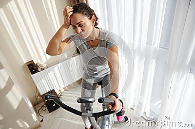 Young african woman feeling exhausted after training on a spin bike Stock Photo