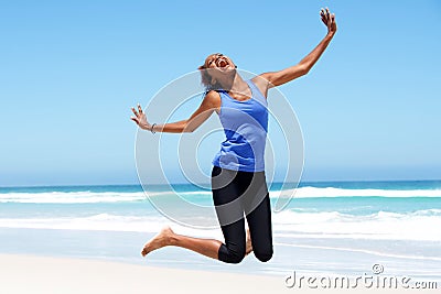 Young african woman jumping with joy at the beach Stock Photo