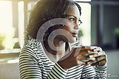 Young African woman deep in thought drinking a coffee Stock Photo