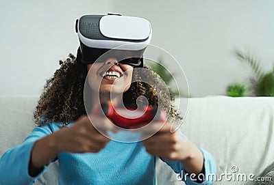 Young African woman playing online video games - Happy gamer having fun on new technology console with virtual reality experience Stock Photo