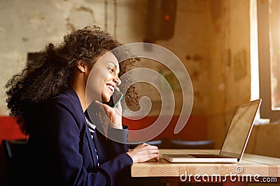 Young african woman relaxing in cafe and making phone call Stock Photo