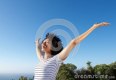 Young african woman standing outdoors with arms raised and laughing Stock Photo