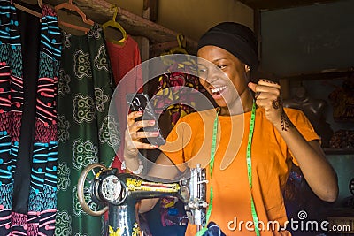 African woman who is a tailor feeling excited and happy and jubilant while viewing content on her mobile phone Stock Photo