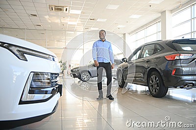 young africanamerican man came to see automobiles in dealership or cars showroom Stock Photo