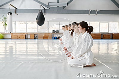 Young aikido students wearing kimono sitting on floor in row Stock Photo
