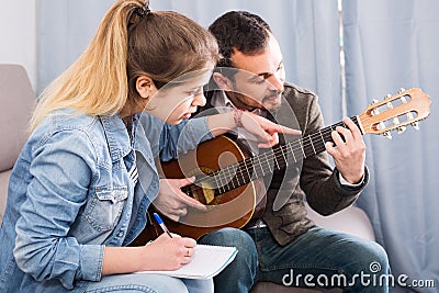 guitar tutor explaining basics to his female client at home Stock Photo