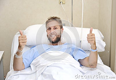 Young American man lying in bed at hospital room sick or ill but giving thumbs up smiling happy and positive Stock Photo