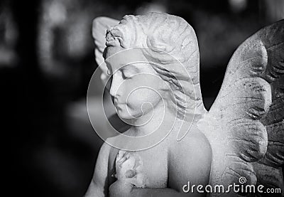 Young angel statue in a London cemetery looks down while praying Stock Photo