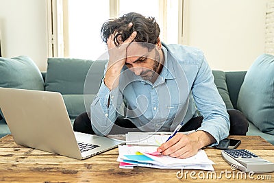 Angry man paying bills as home with laptop and calculator Stock Photo