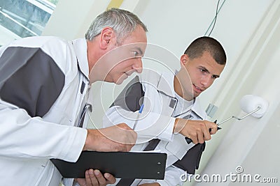 young apprentice being assessed while painting with roller Stock Photo