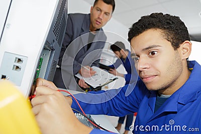 Young apprentice electrician using multimeter on electrical appliance Stock Photo