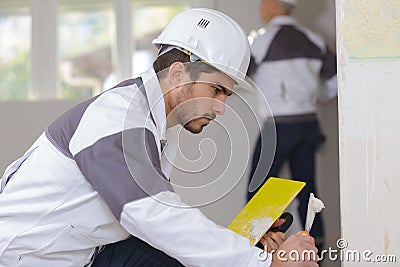 Young apprentice plasterer working on indoor wall Stock Photo