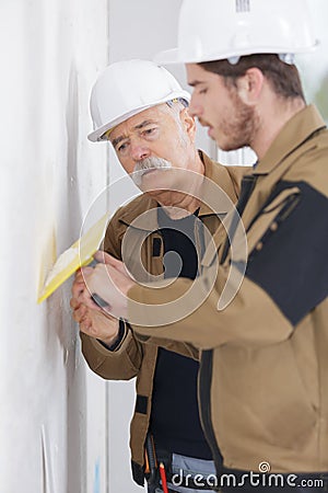 Young apprentice with professional plasterer Stock Photo