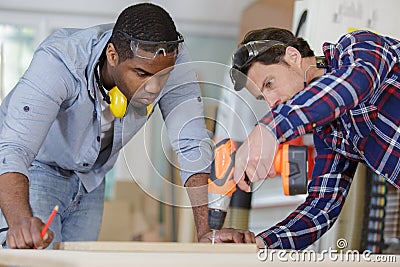 young apprentice and wood professional drilling wood Stock Photo