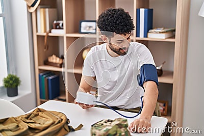 Young arab man army soldier using tensiometer at home Stock Photo