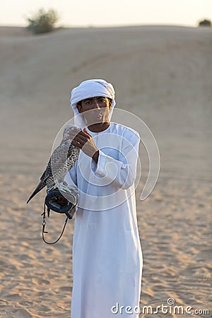 Young arab man holding a hawk in the desert near Dubai, UAE Editorial Stock Photo