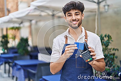 Young arab man waiter using data phone and credit card at restaurant Stock Photo