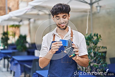 Young arab man waiter using data phone and credit card at restaurant Stock Photo