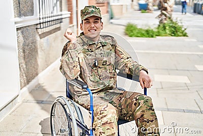 Young arab man wearing camouflage army uniform sitting on wheelchair screaming proud, celebrating victory and success very excited Stock Photo