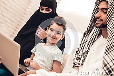 Young Arabic Family Using Laptop on Sofa at Home Stock Photo